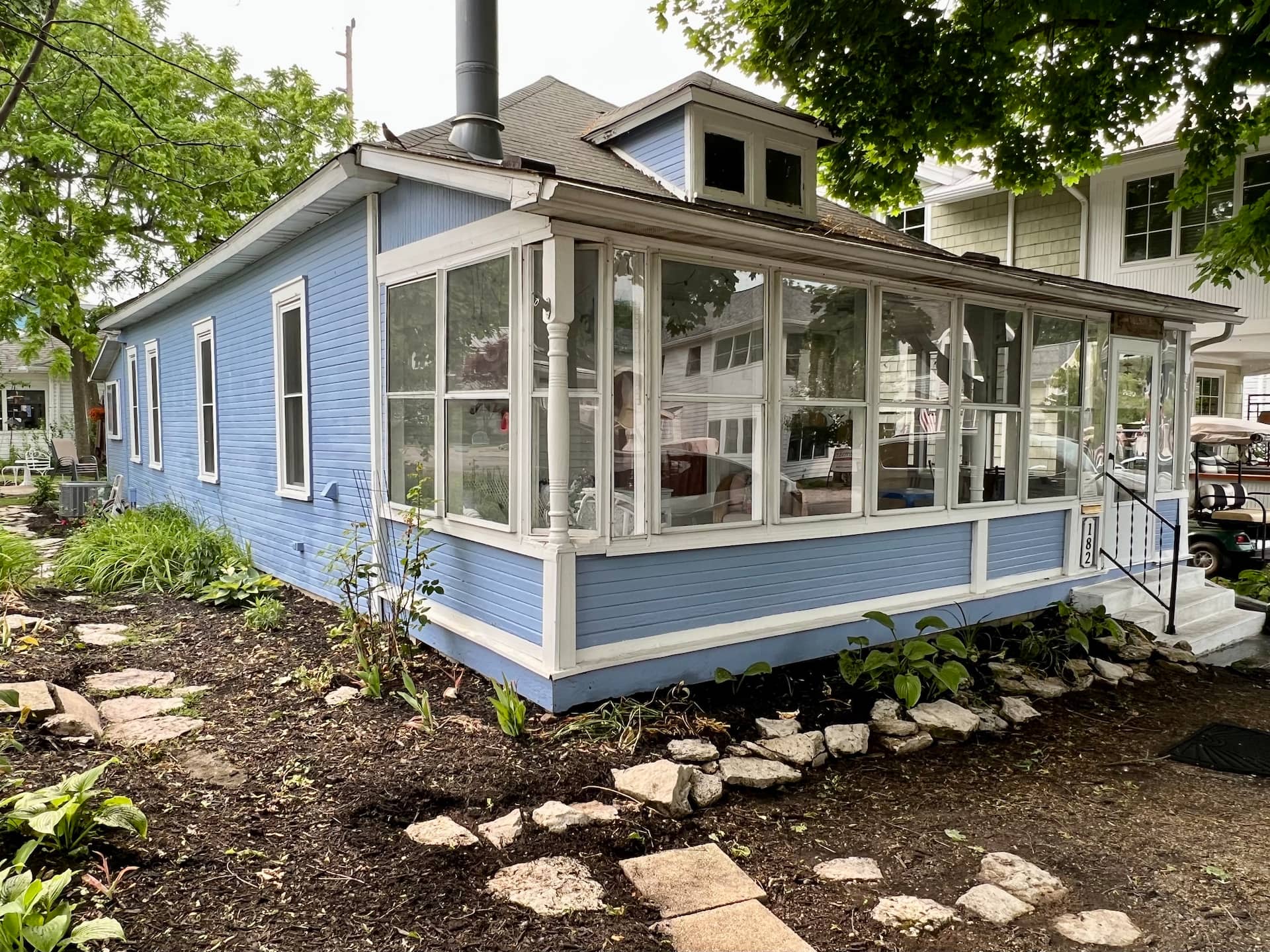 The blue cottage from the garden, its glassed-in porch wrapping the front