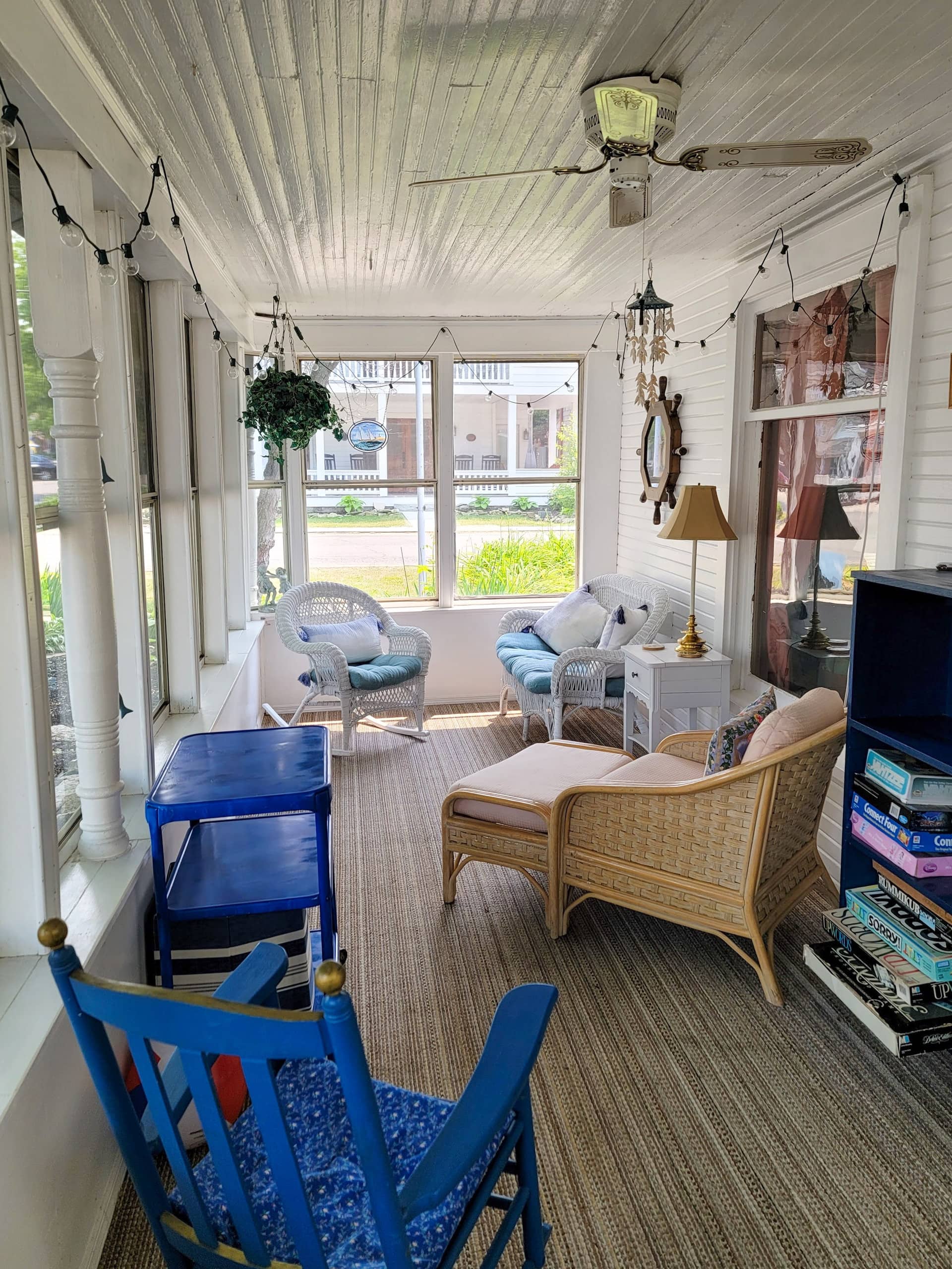 Wicker chairs and a painted blue rocker on the enclosed porch