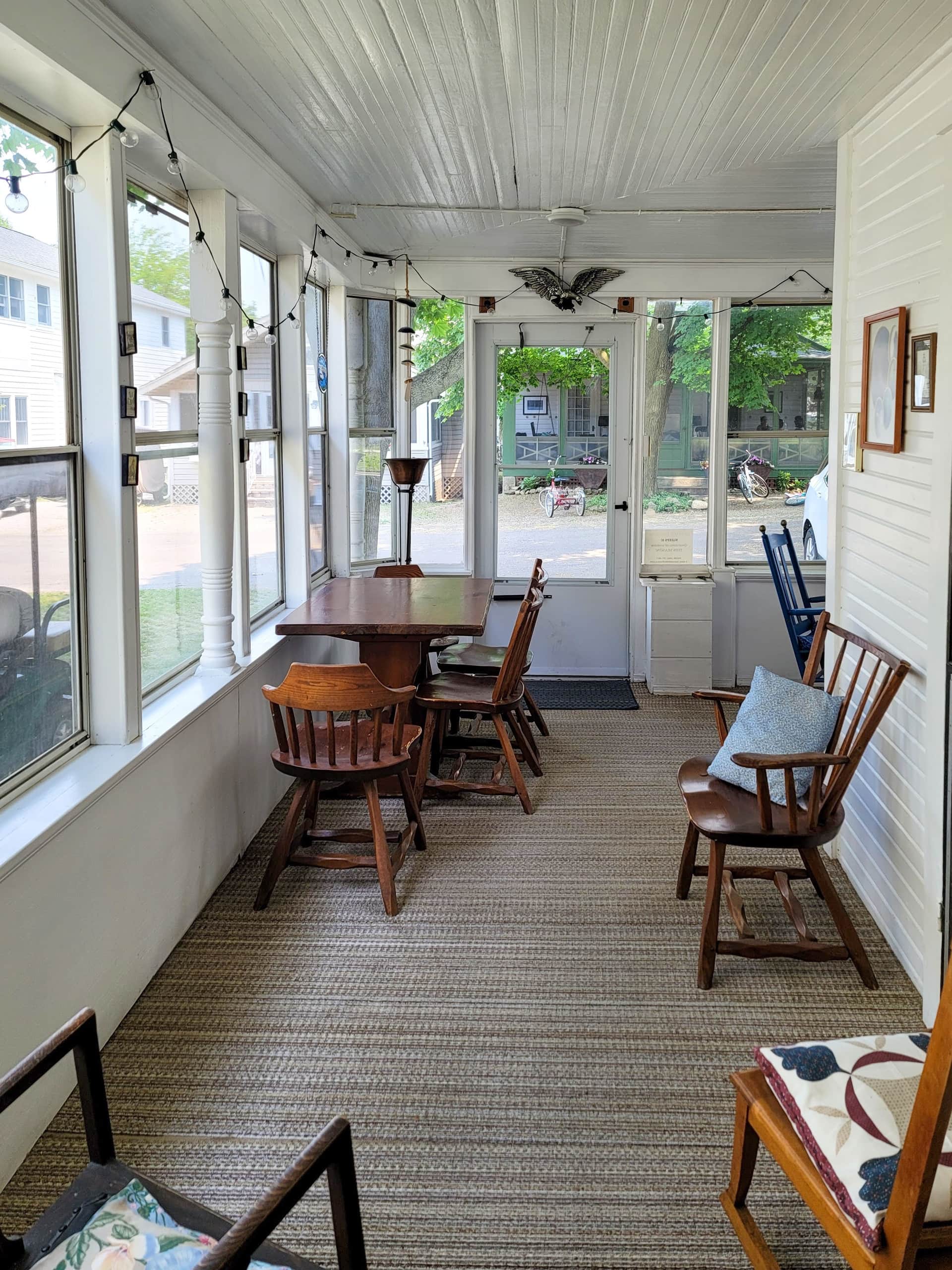 A dining table and spindle chairs along the porch windows