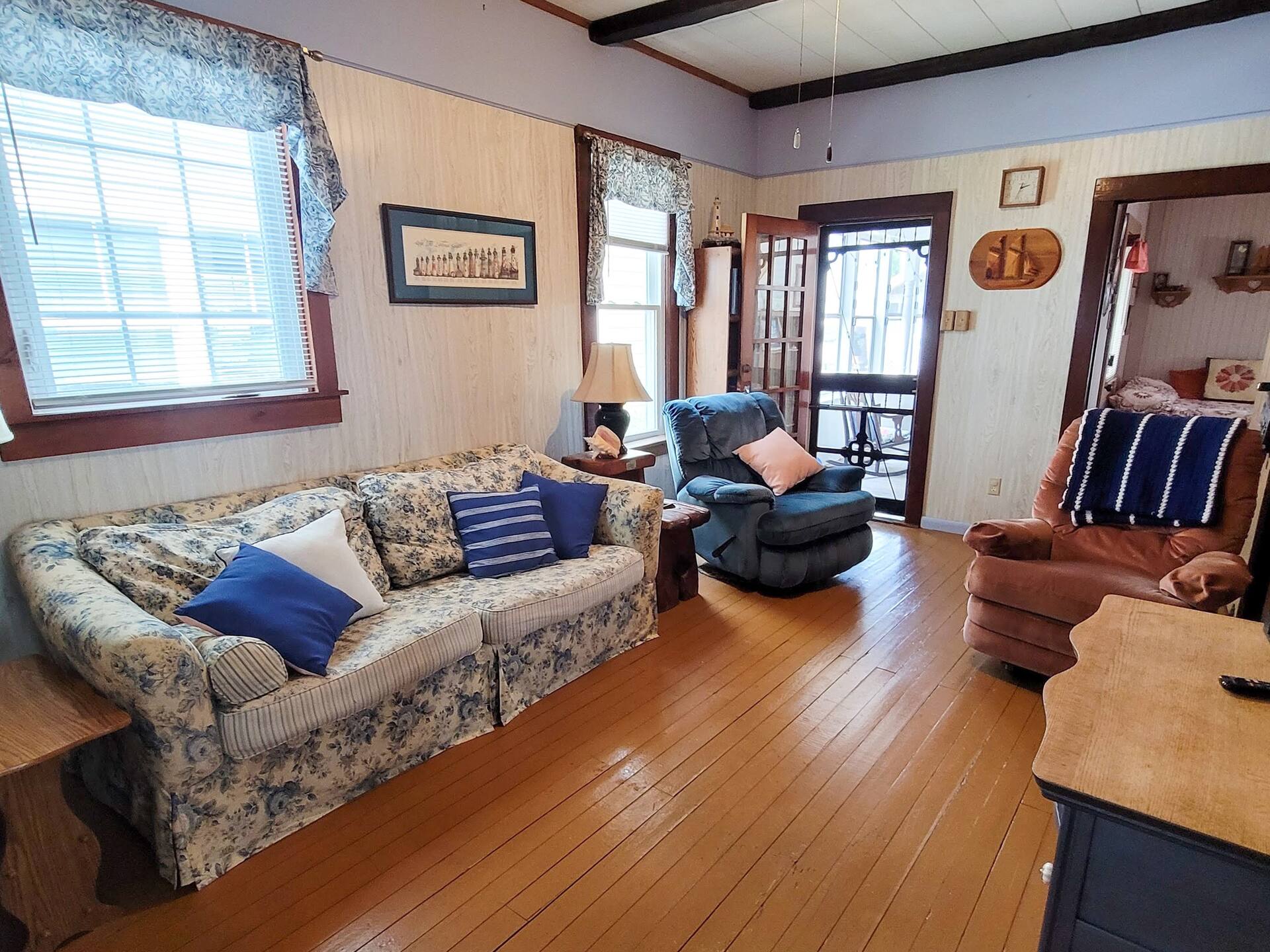 Living room with a floral sofa, wood floors and tall windows