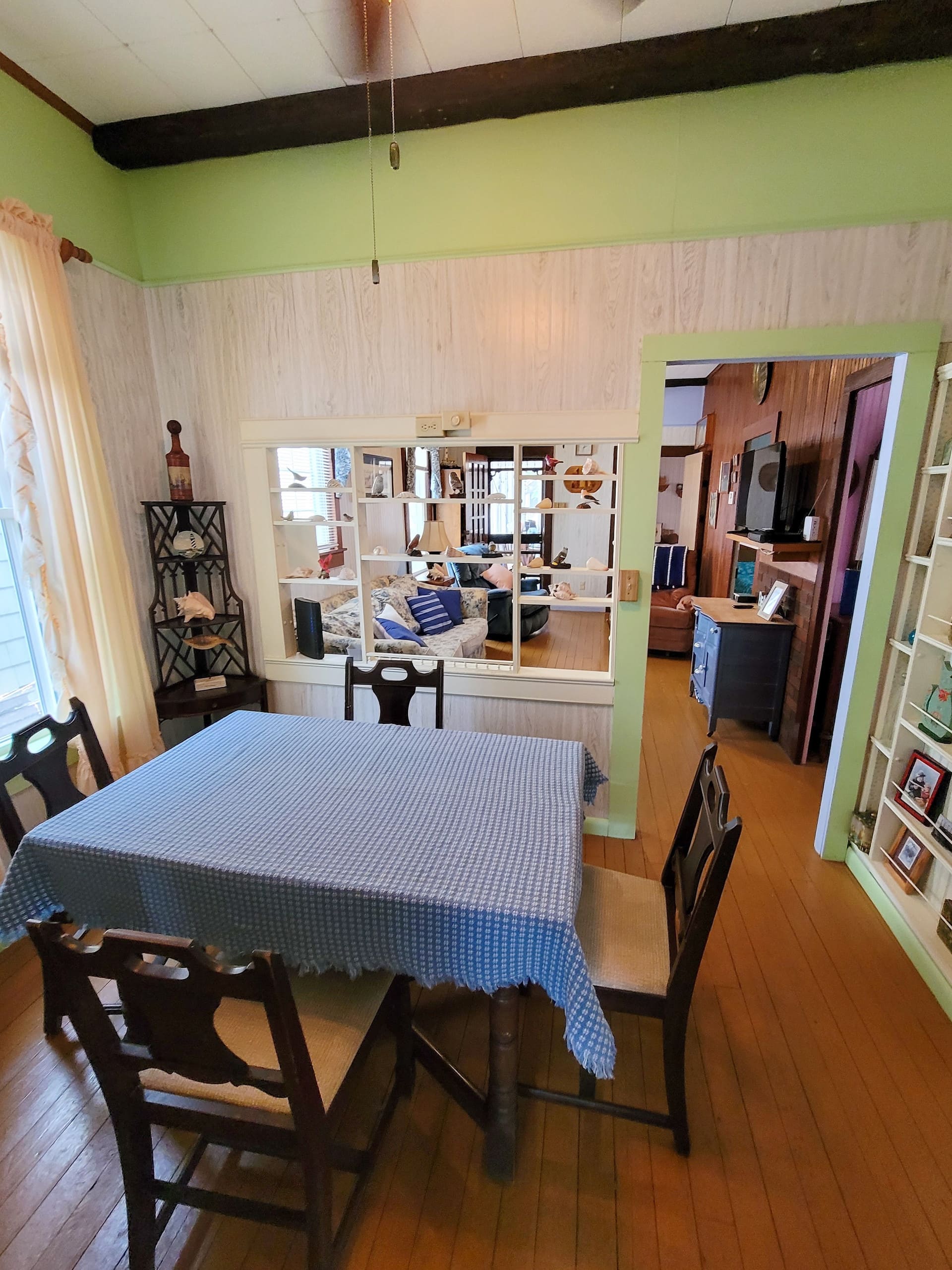 Dining table set under a green wall, kitchen beyond