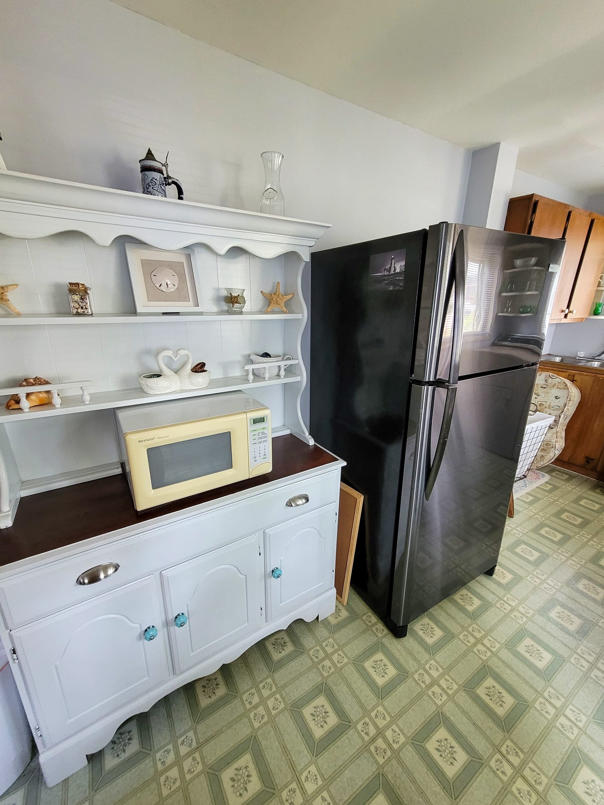 Utility corner with a white hutch and full-size fridge